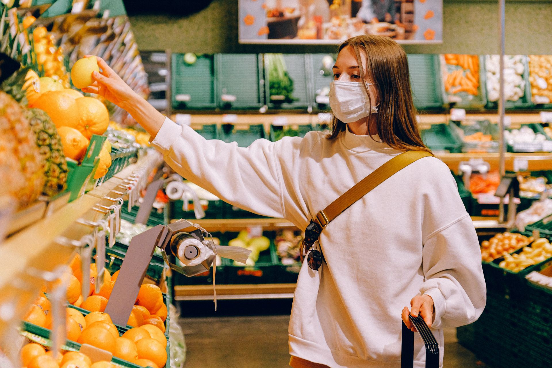 Woman wearing a mask in the supermarket buying fruit