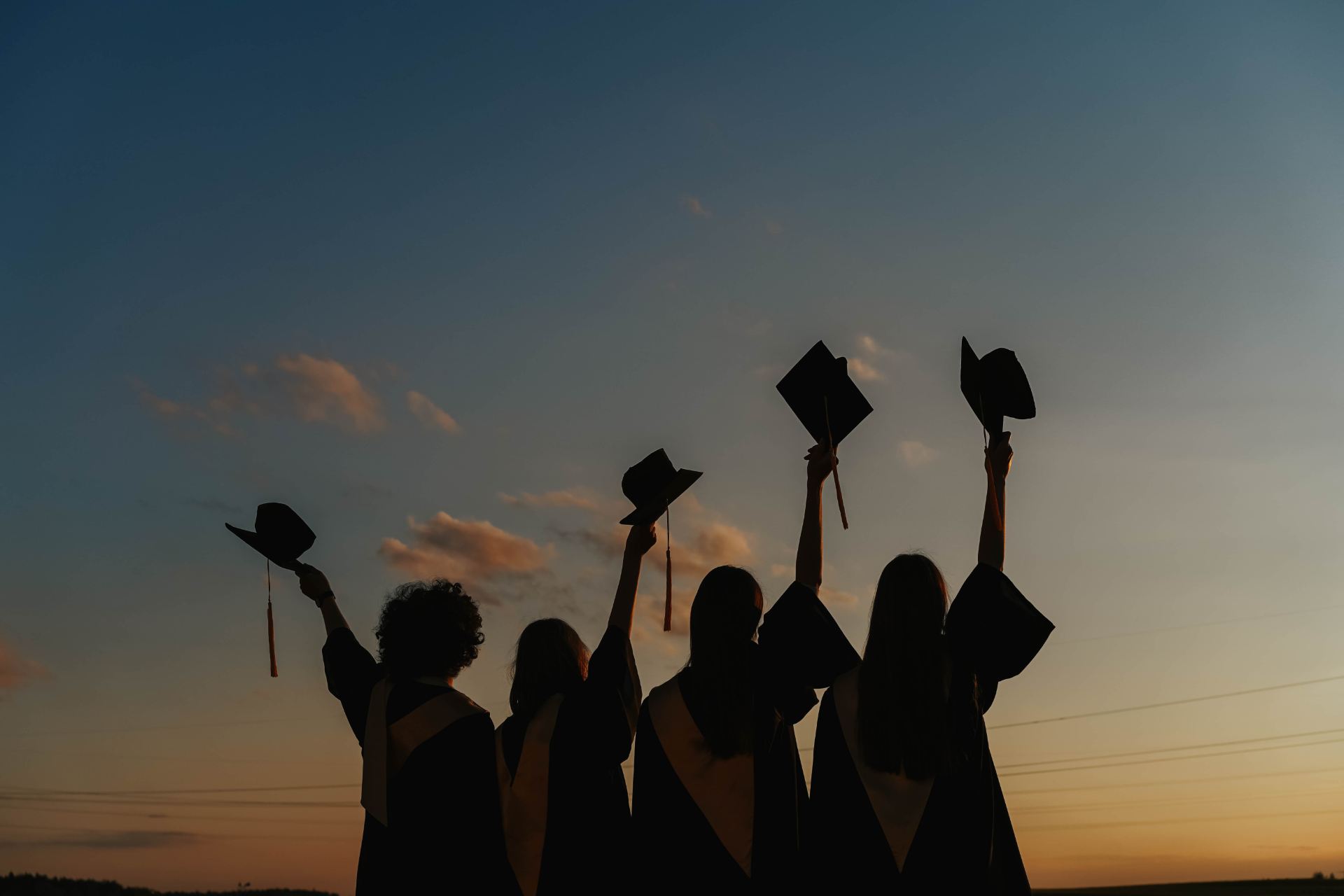 graduates in front of a sunset