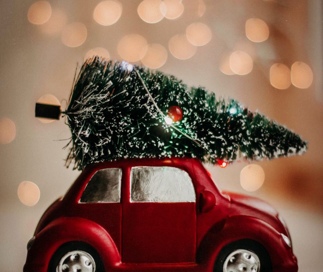 a toy red car with a tiny toy Christmas tree on it