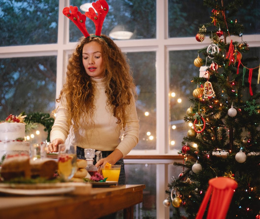 a girl preparing a Christmas dinner with a Christmas tree standing in the corner