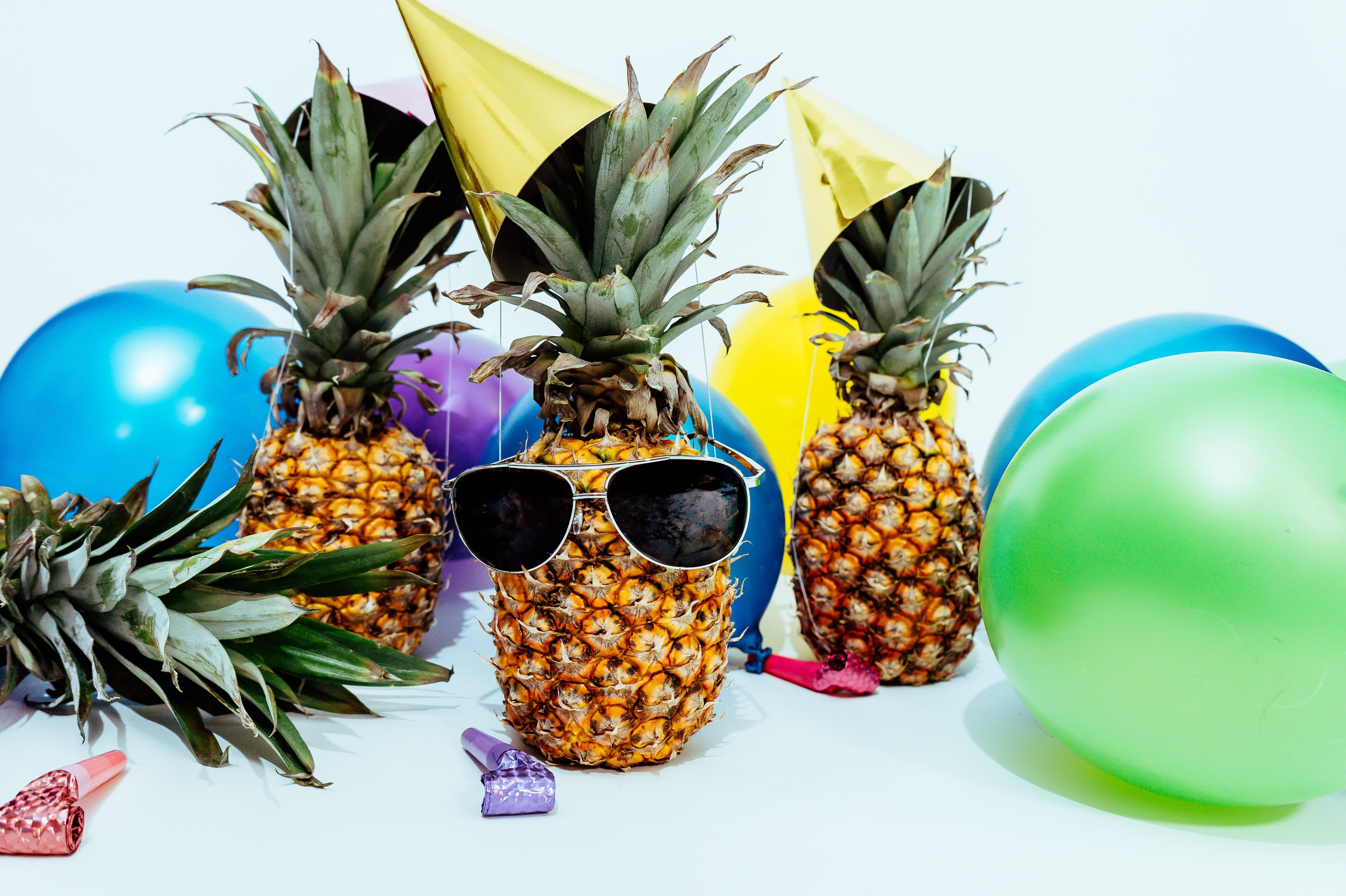 A funny image of balloons and pineapples, one of which is wearing sunglasses.