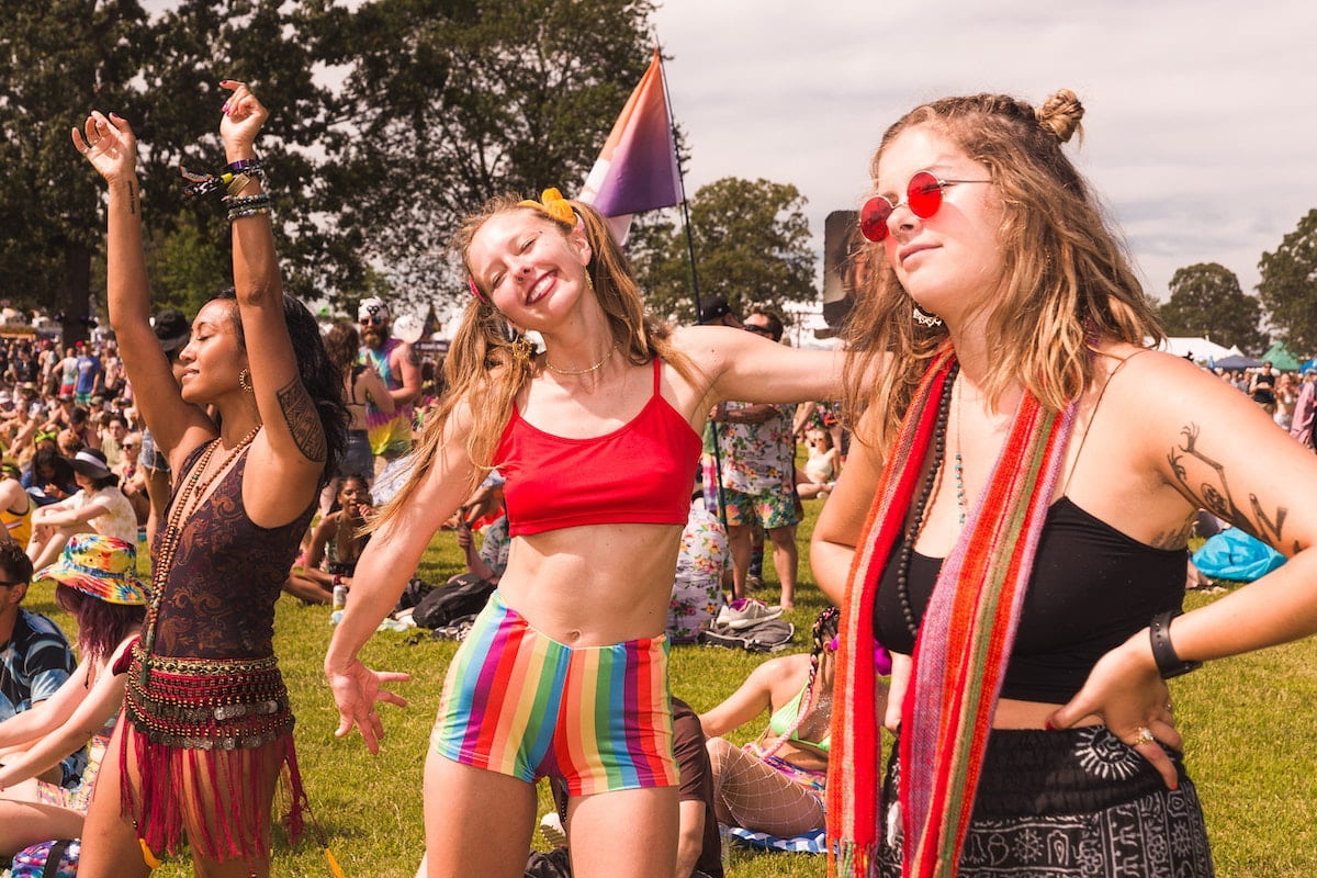Young women at a festival in a field wearing bright accessories.  